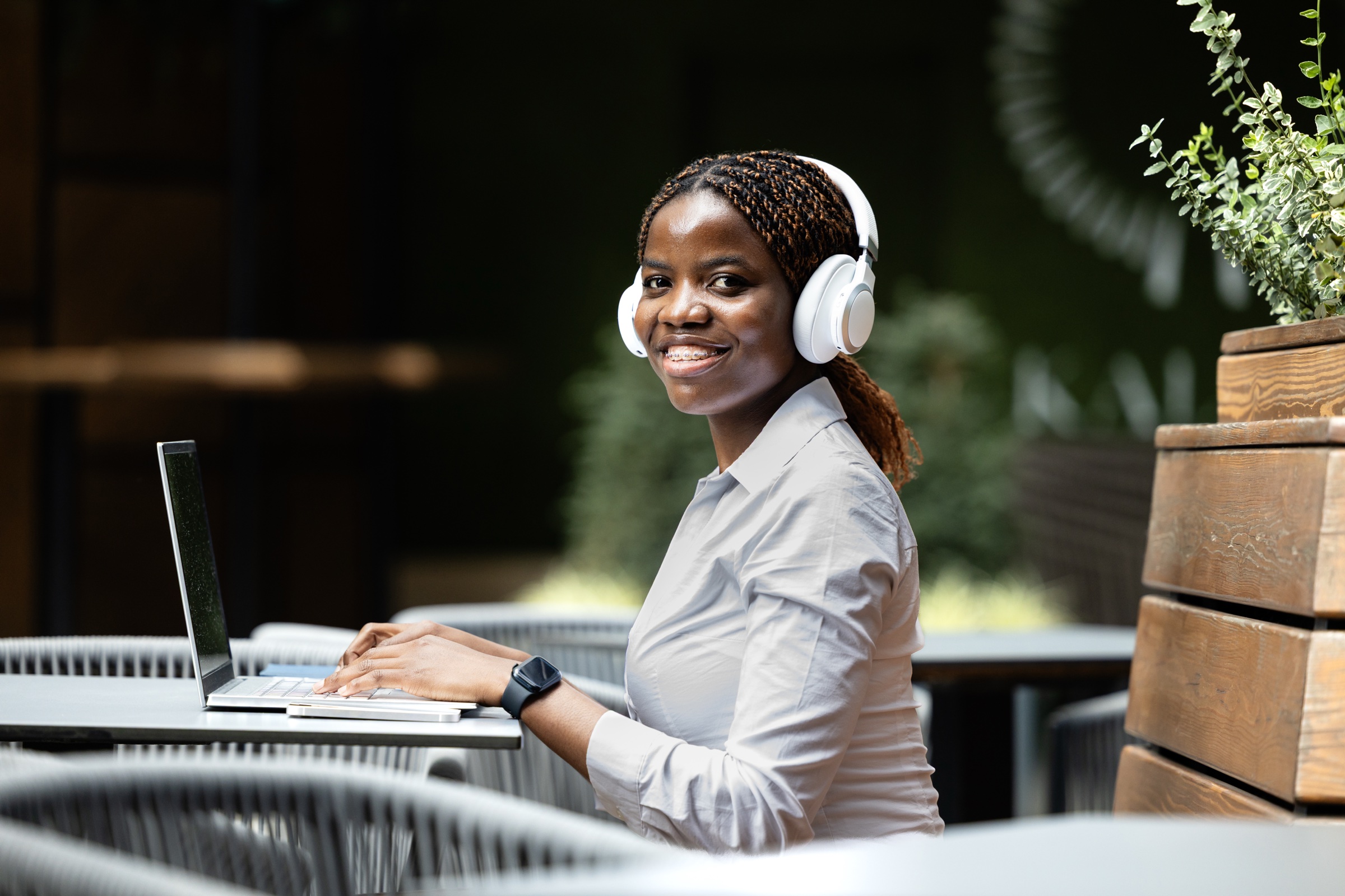 A team member joining the WorkSystem from an outdoor workspace, headphones on, laptop open